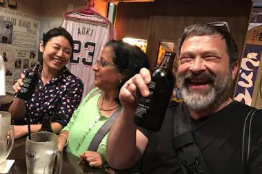 Guide and guests toasting with beer at a Sangenjaya standing bar