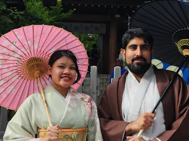 Couple in kimono with paper umbrellas at a shrine