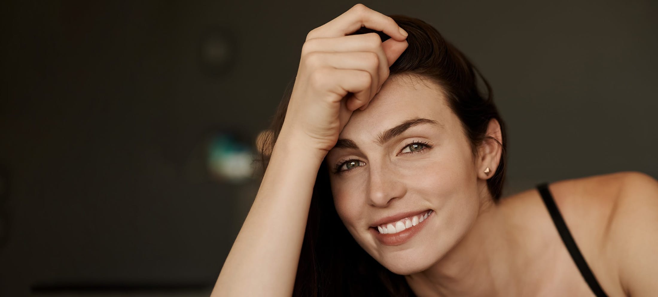 Woman smiling with her arm rested against her face