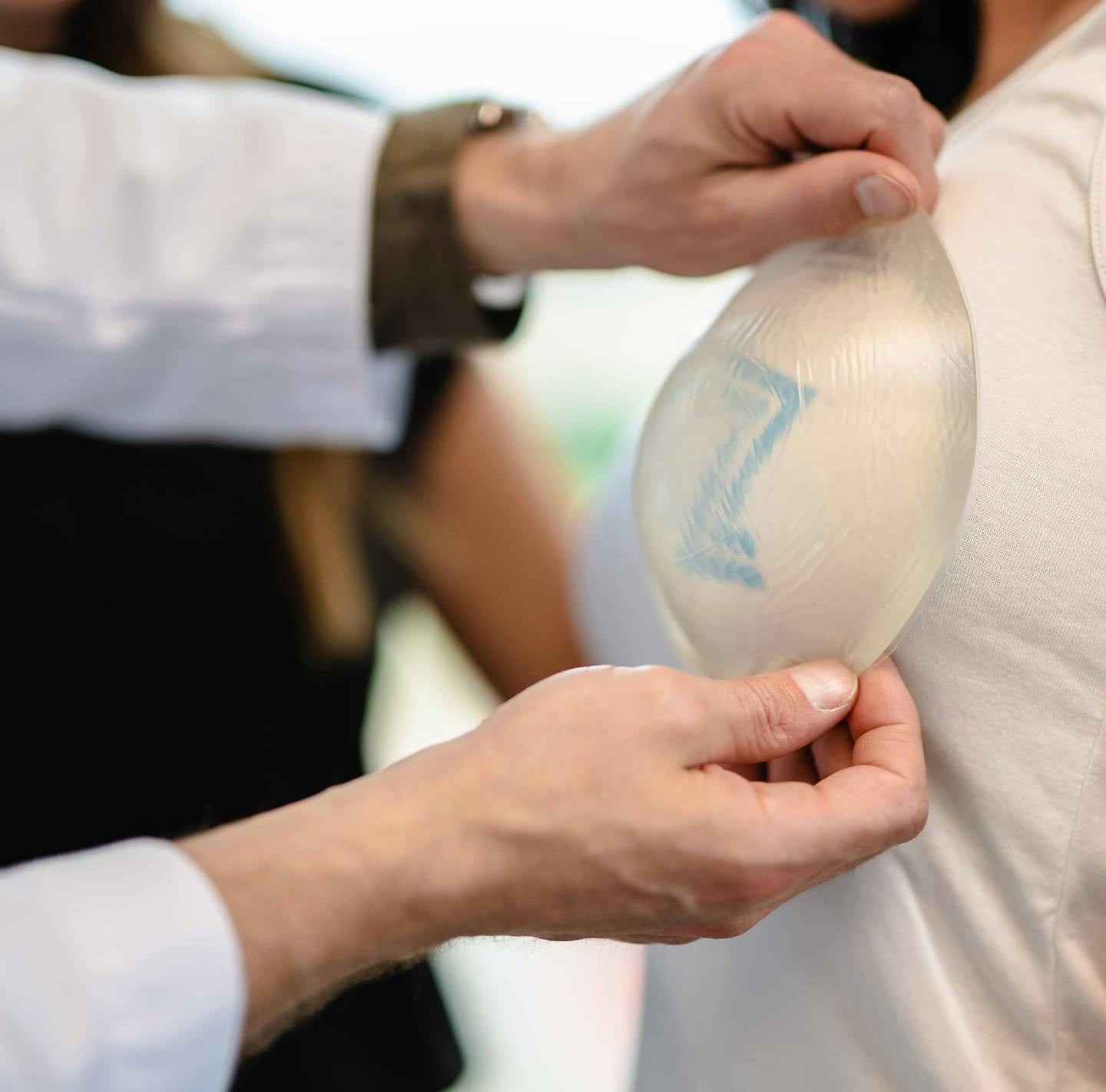 Dr. Piazza holding a sample implant to a patient