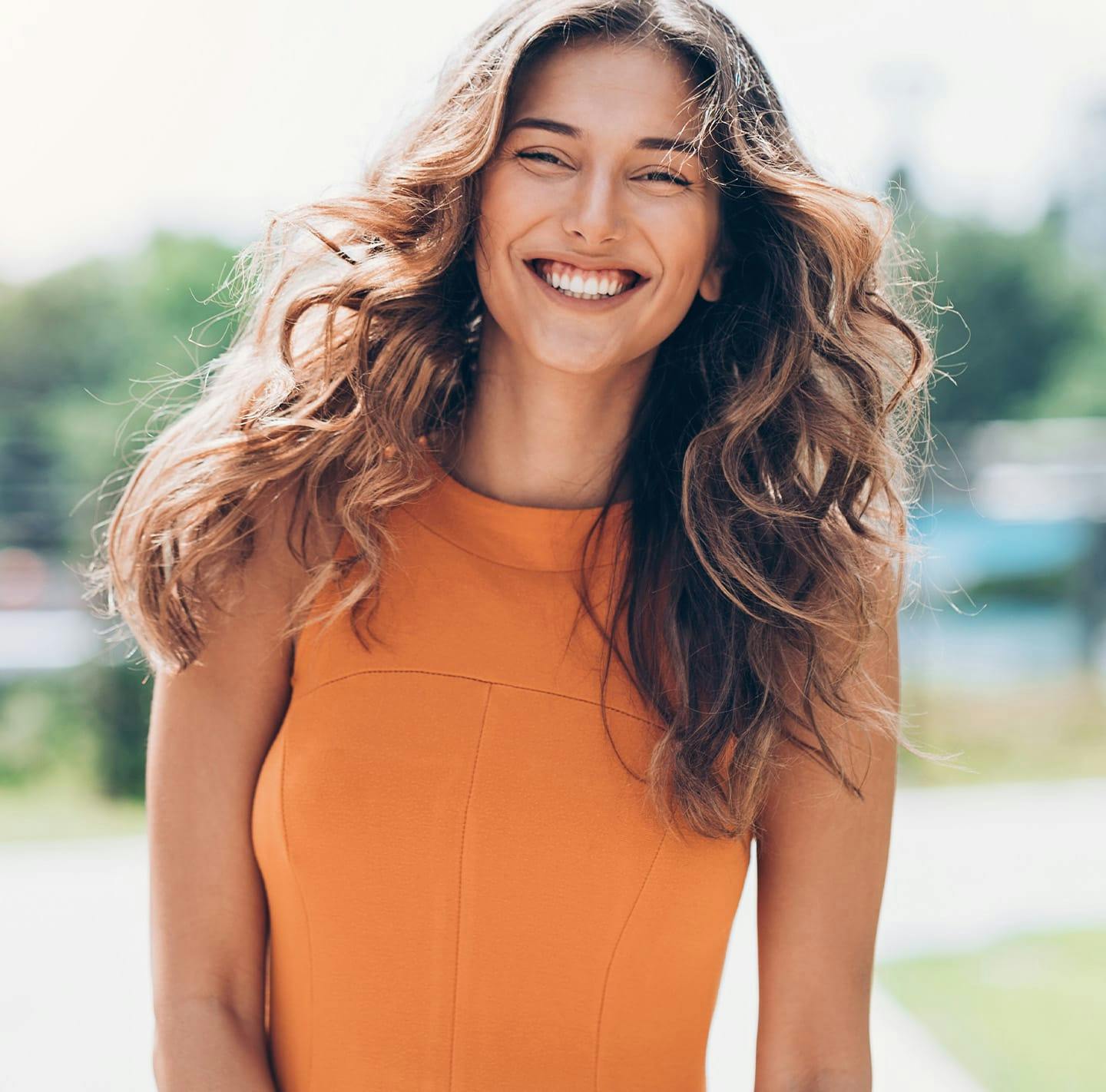 Brunette woman in orange top smiling