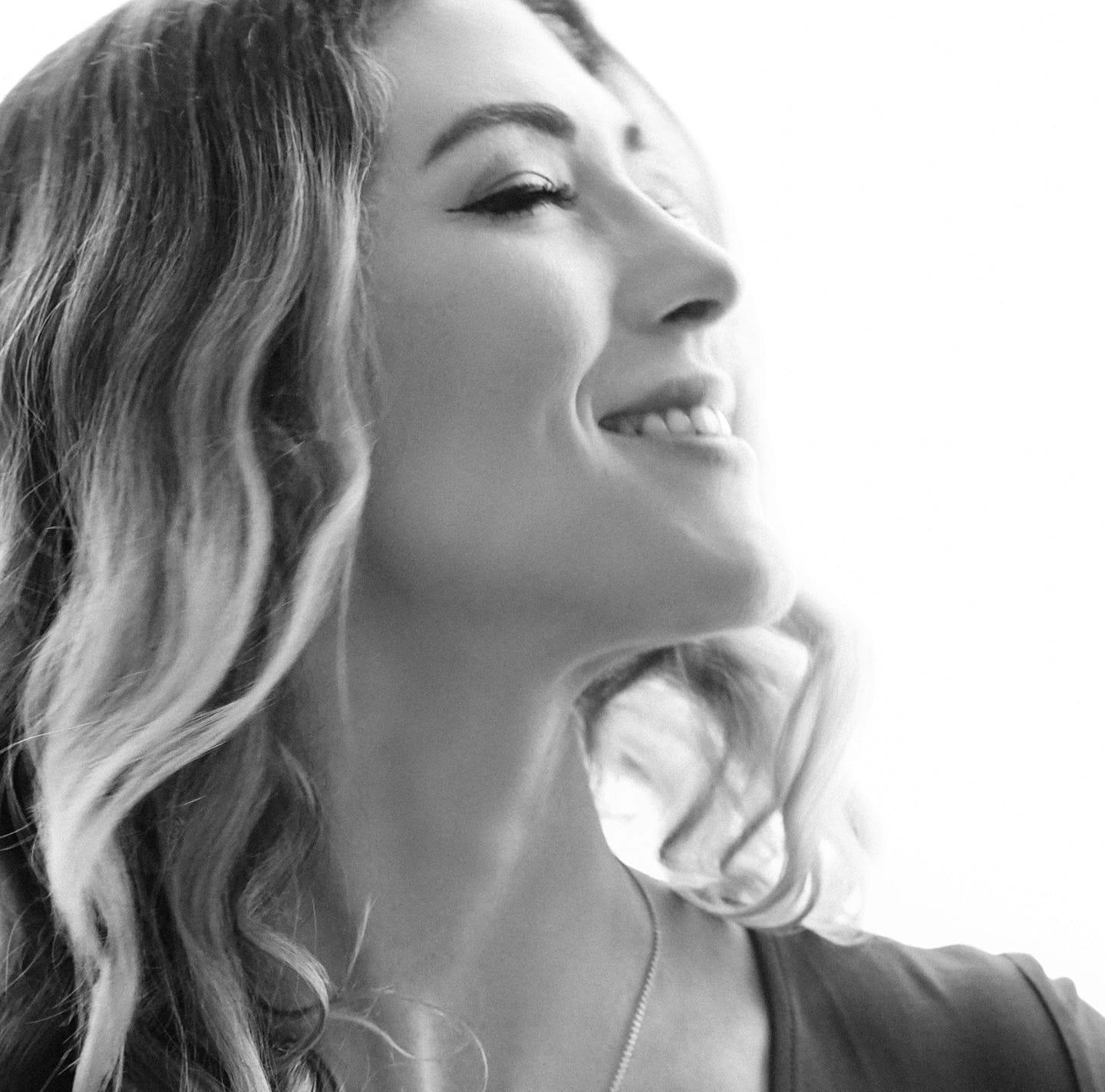 Black and white image of a woman tilting her face upwards while smiling