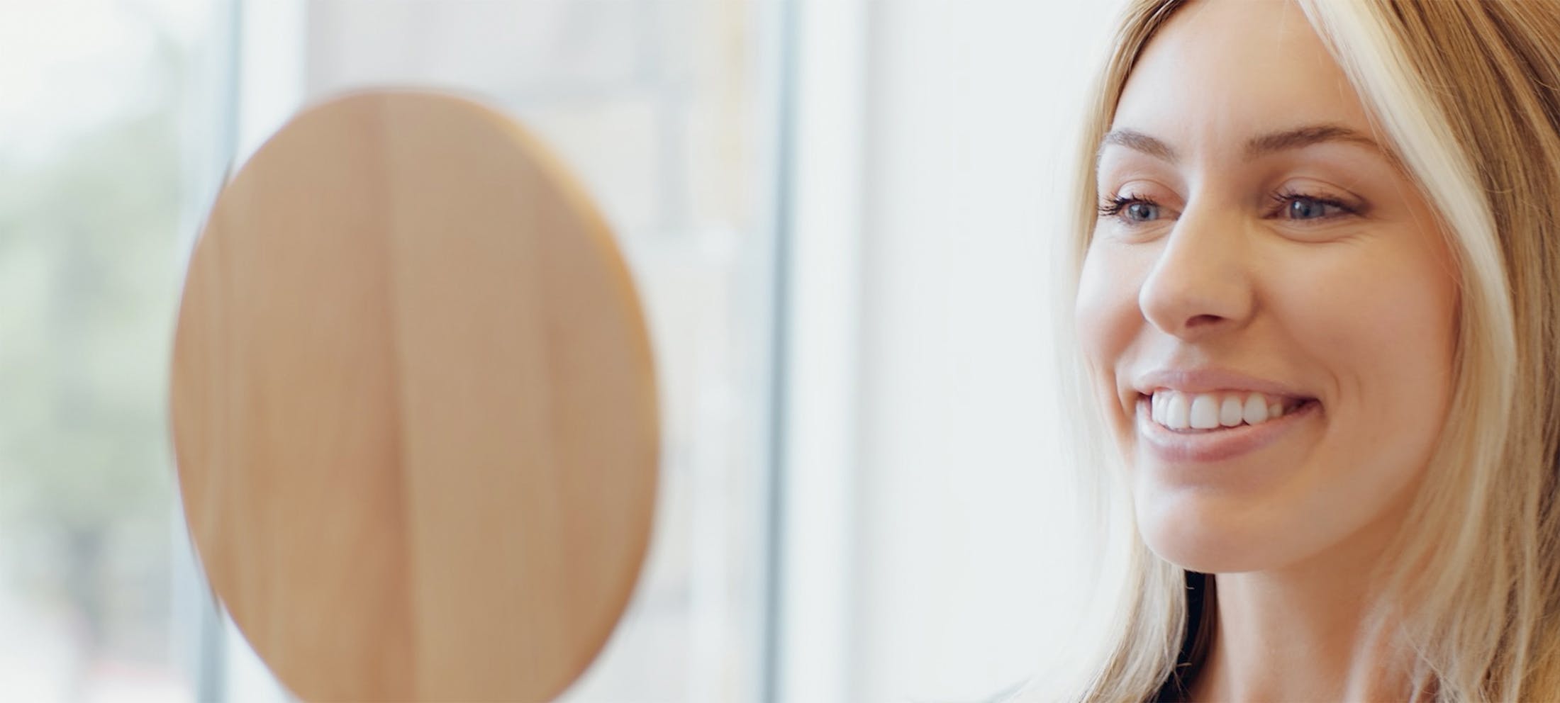 Woman looking in a handheld mirror