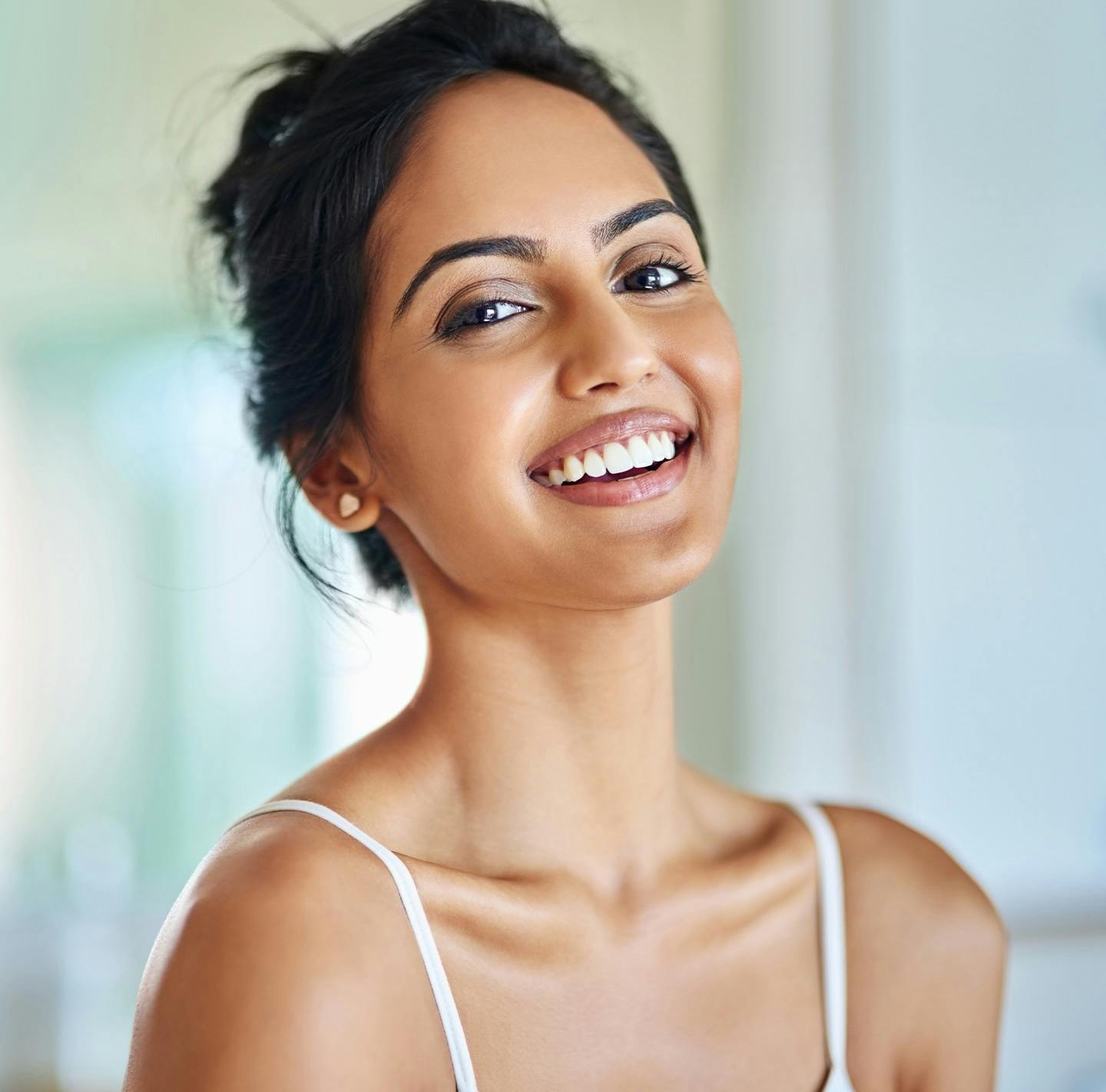 smiling woman with a white top and black hair looking up