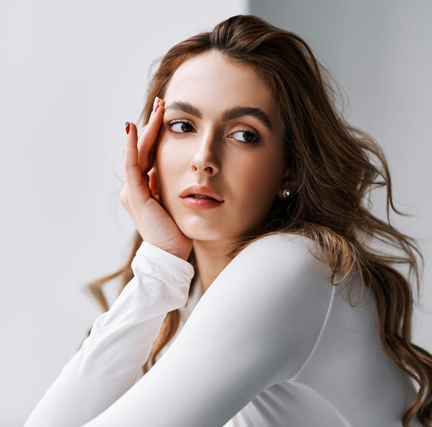 woman in white shirt posing with her hand on her face