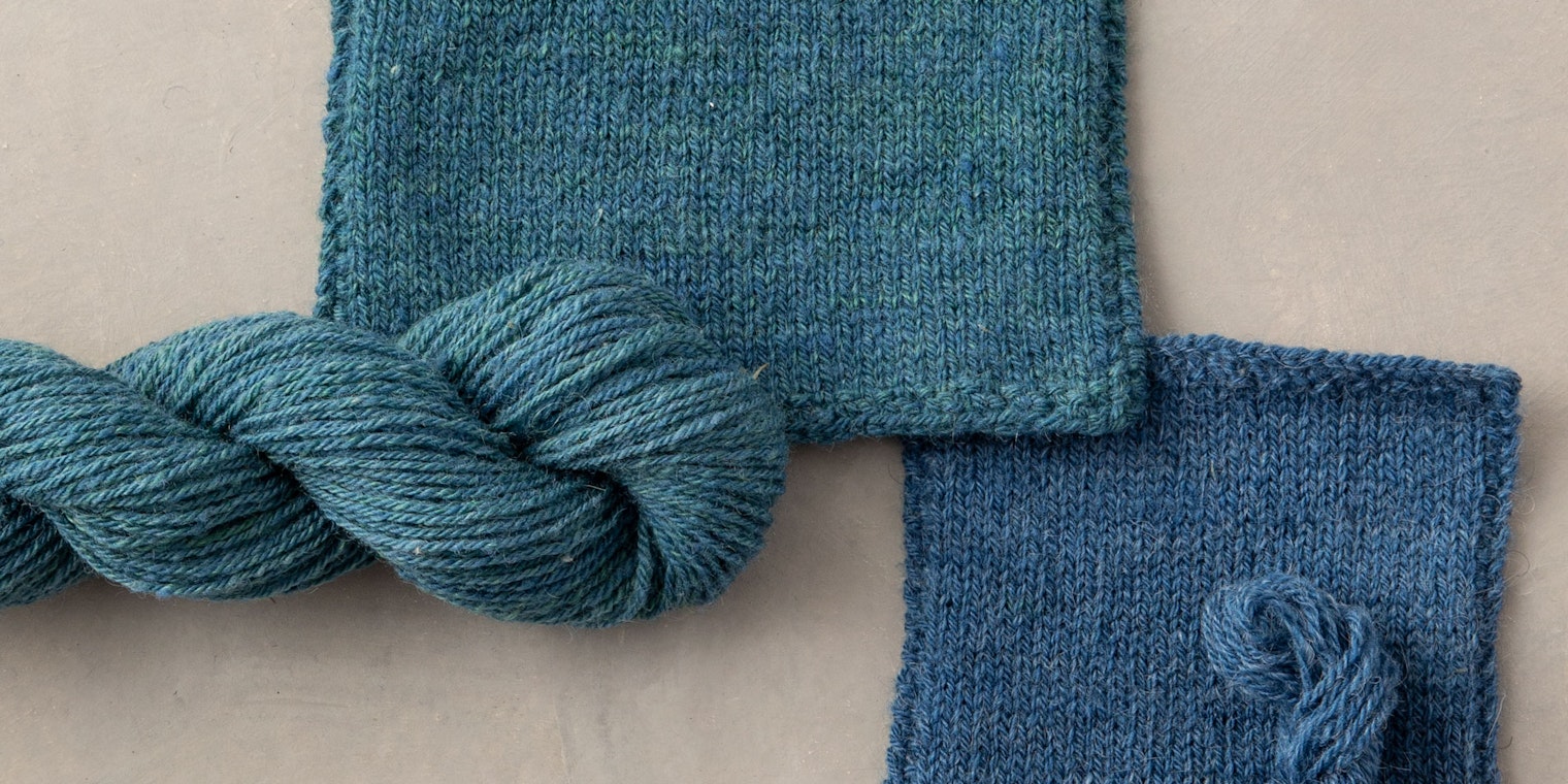 two blue knitted swatches and skeins of handspun yarn