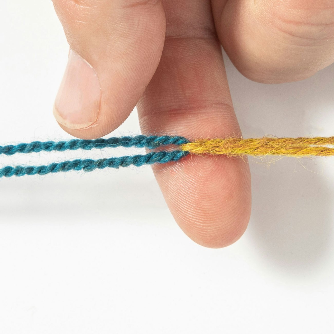 Hand with teal and mustard yarn