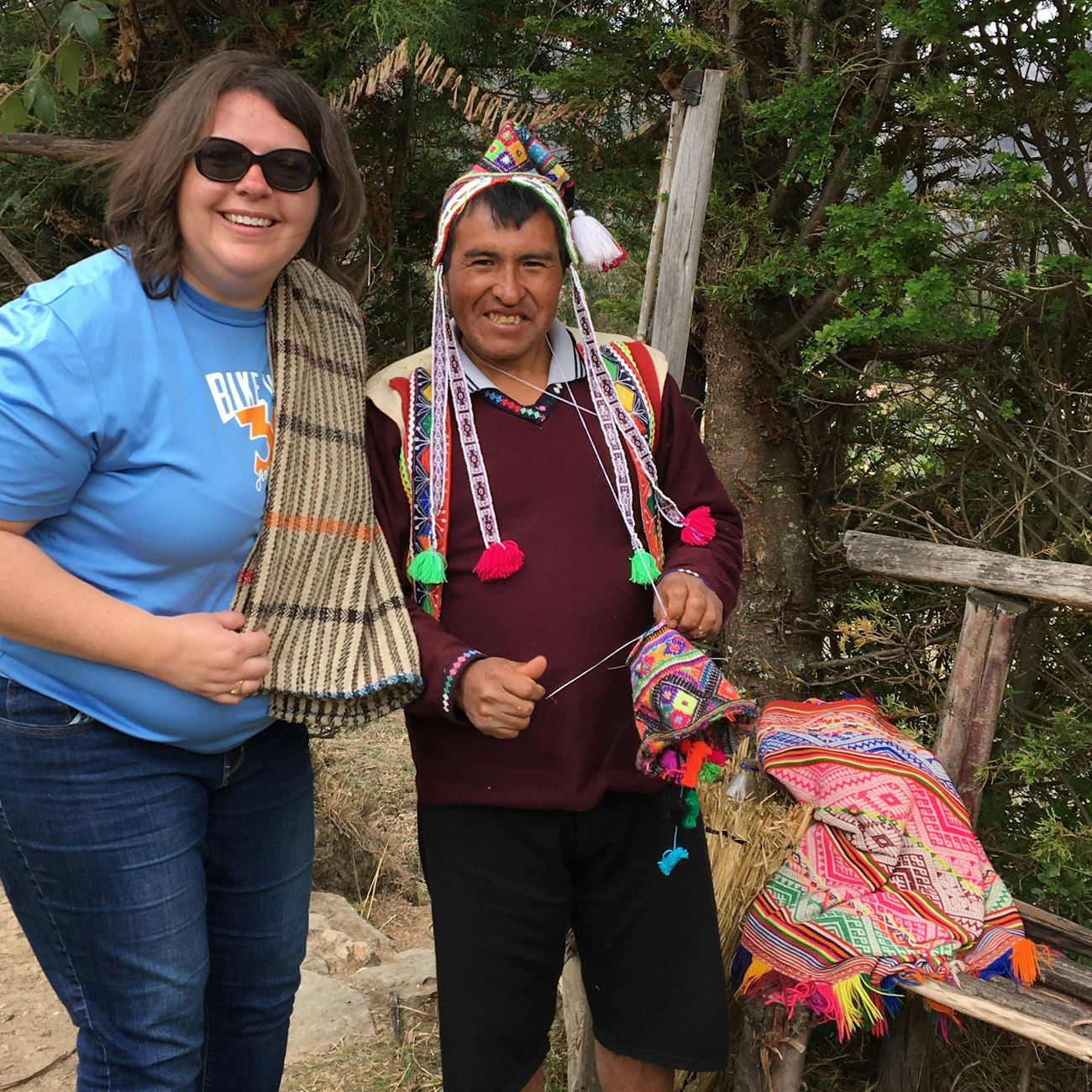 White woman standing next to Peruvian man, holding knitting and wearing chullo hat