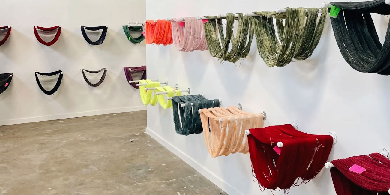 Skeins of colorful wool yarn hanging on hooks in white room