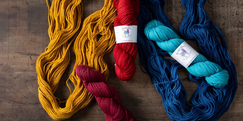 Skeins of gold, maroon, red, indigo, and teal yarn