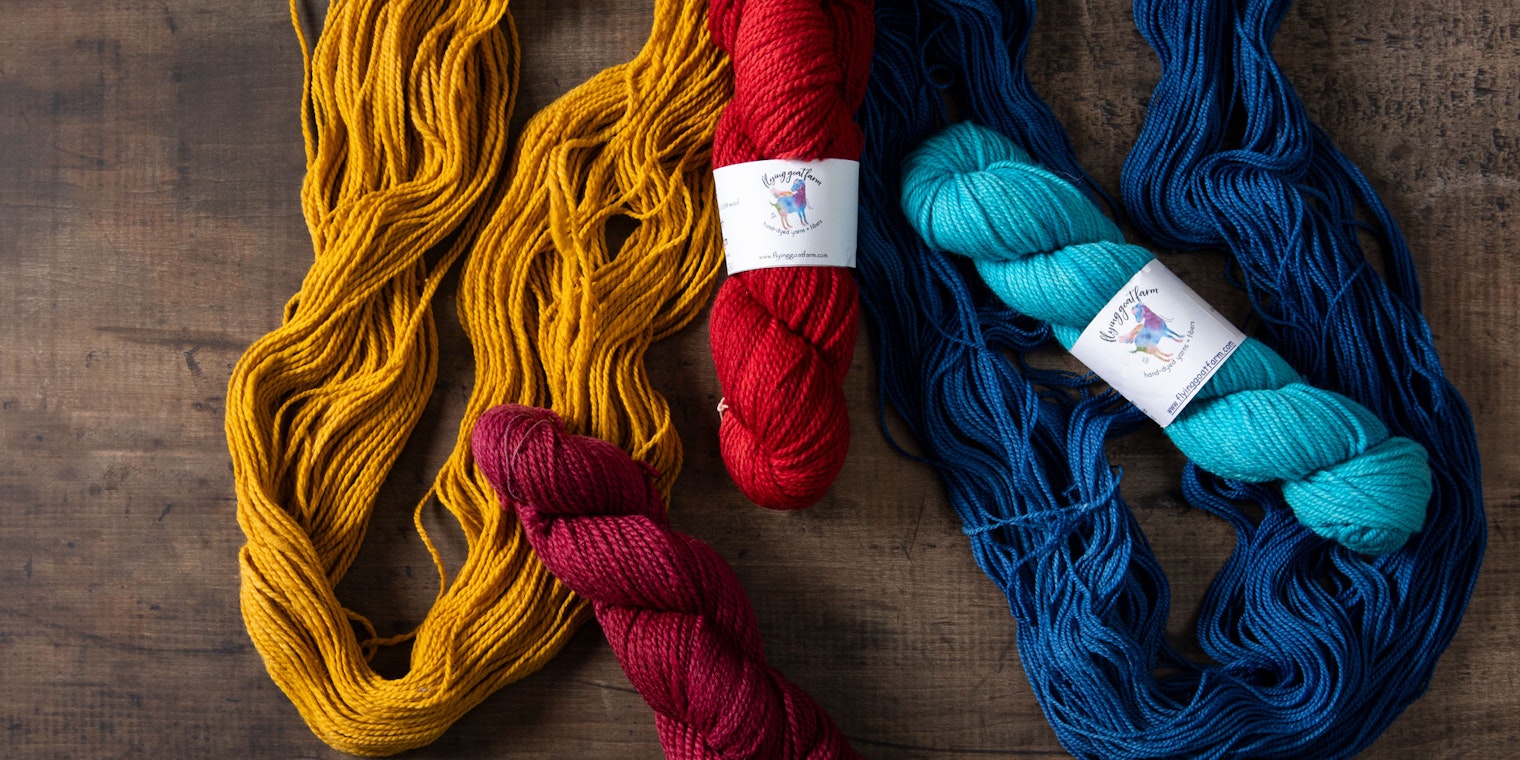 Skeins of gold, maroon, red, indigo, and teal yarn