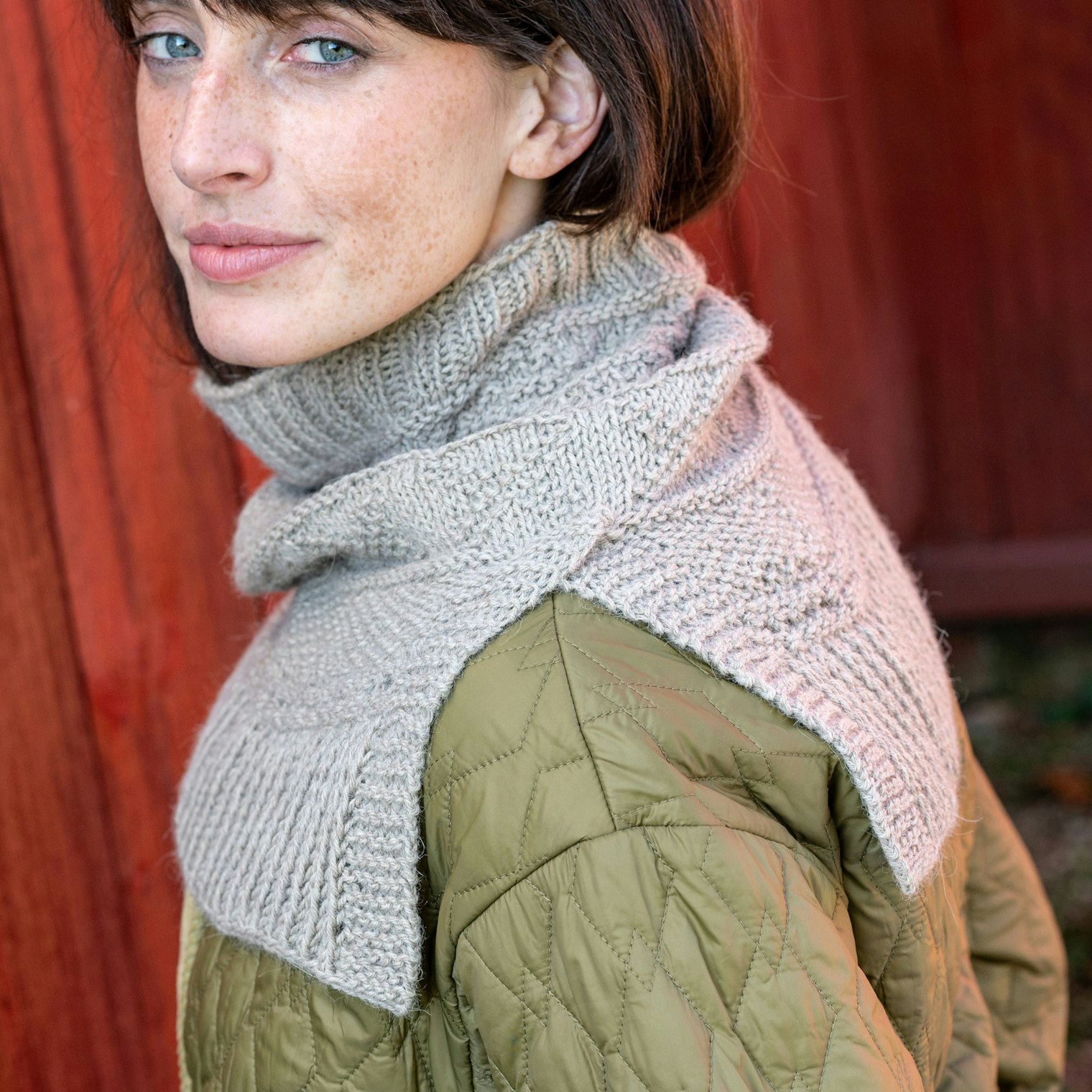 Woman in tan-colored cowl slit over left shoulder