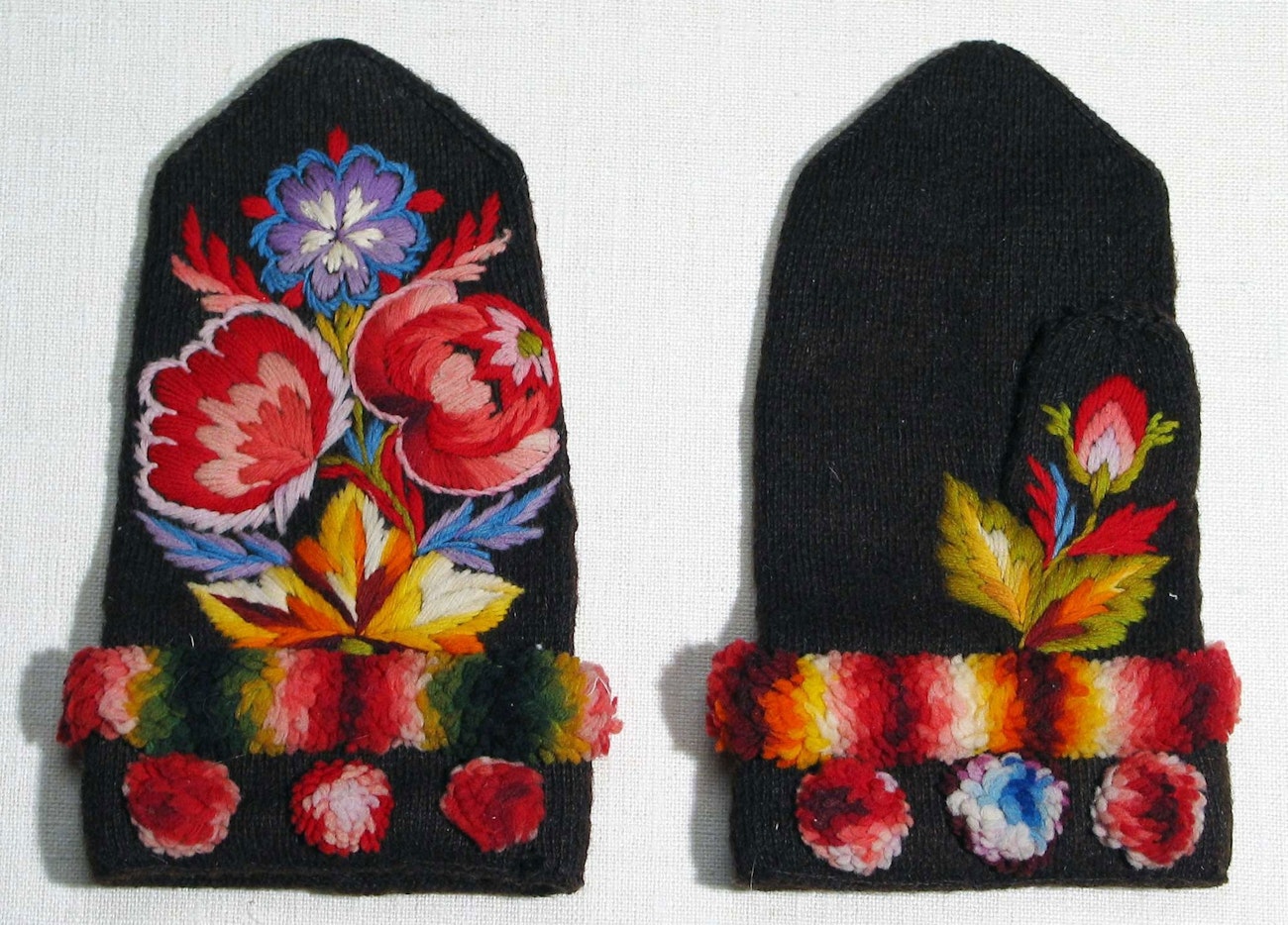 Black mittens worked in tvaandsstickning and embroidered with flowers and fringe