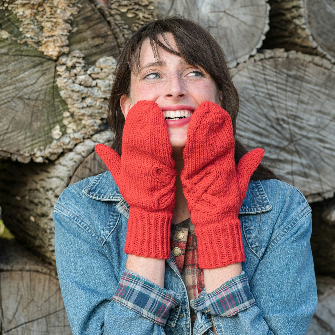 Brown-haired woman wearing red mittens up to her face