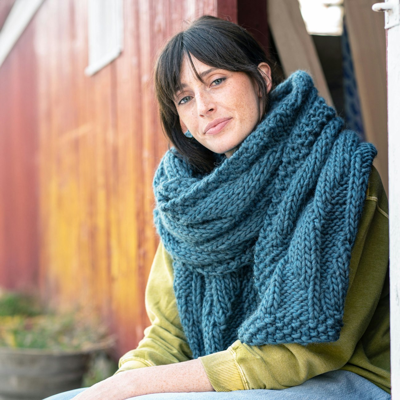 Model with teal scarf wrapped several times around