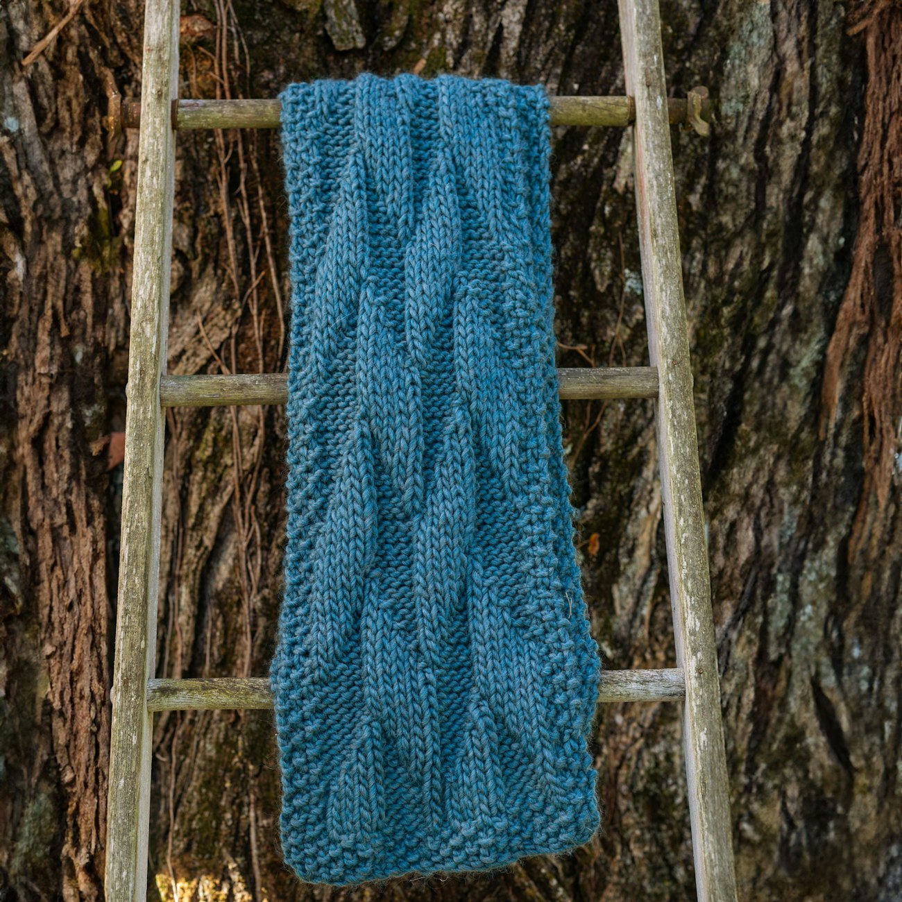 Teal knitted scarf hangs on ladder