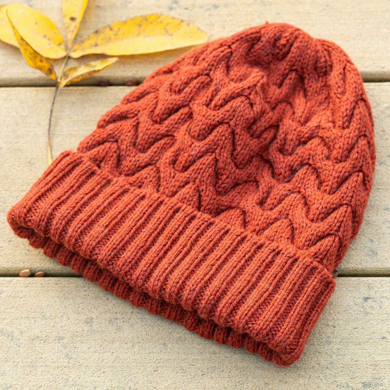 Dark pumpkin cabled hat with yellow leaf