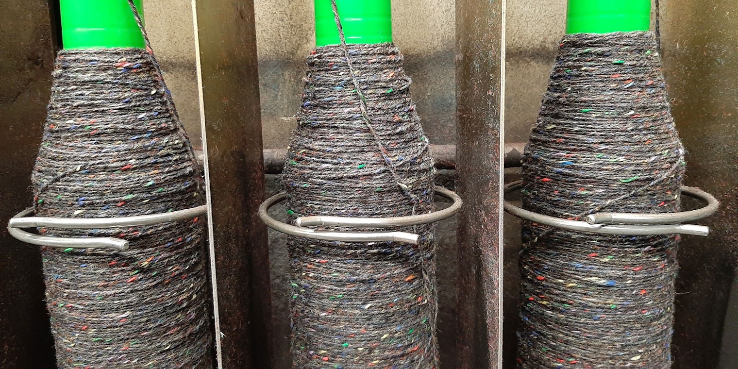 Three spinning bobbins filling with multicolored tweed yarn