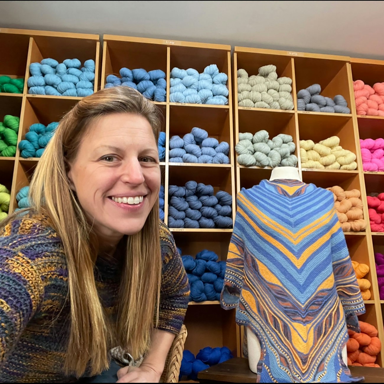 Woman with cubbies filled with colorful hanks of yarn