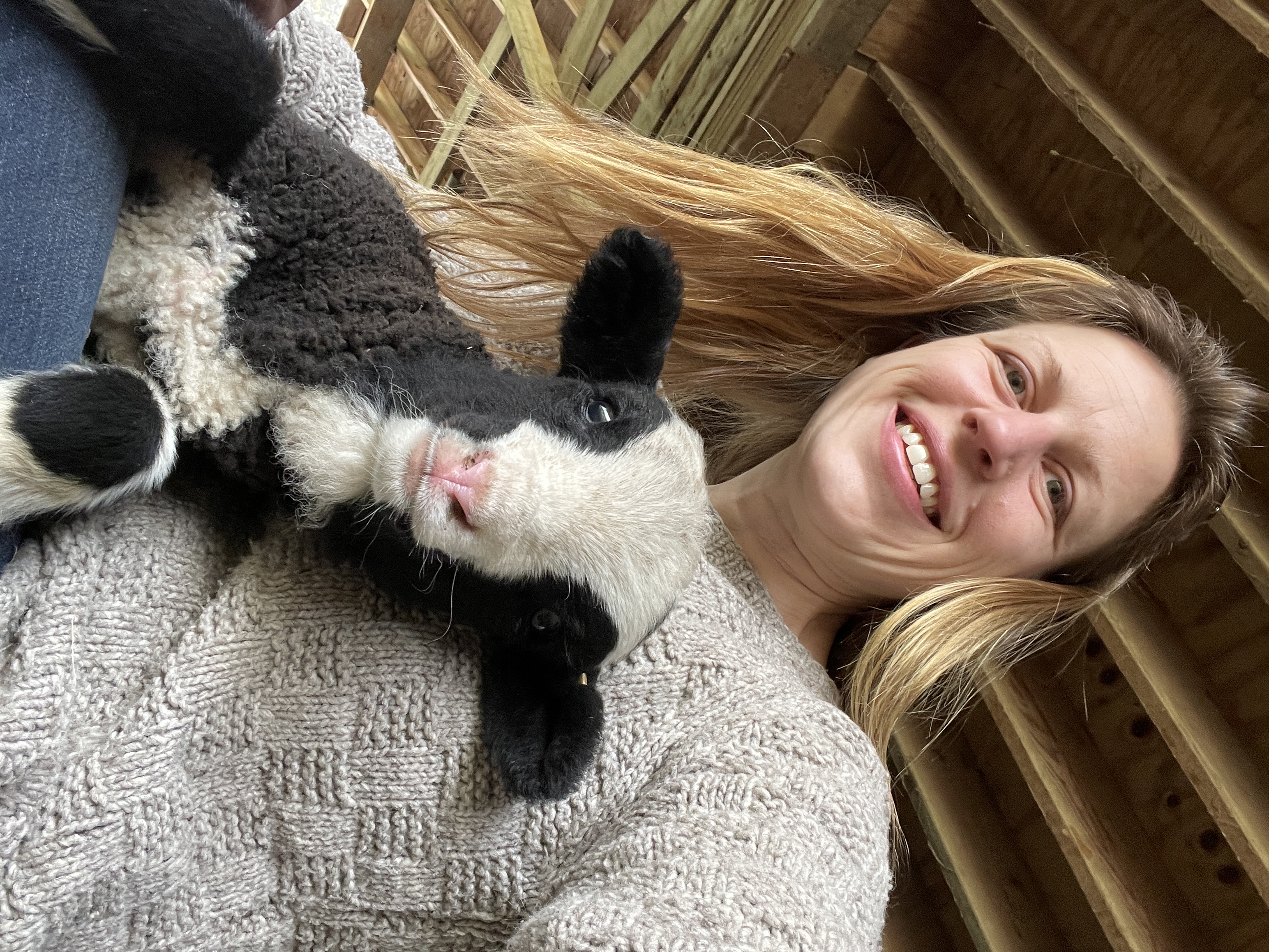 Woman with blond hair holds black-and-white lamb
