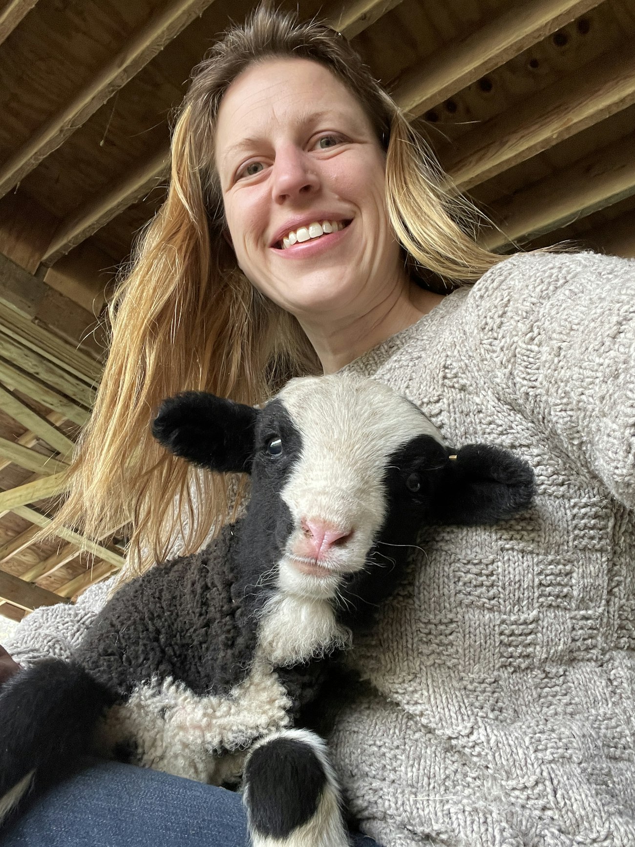 Woman with blond hair holds black-and-white lamb