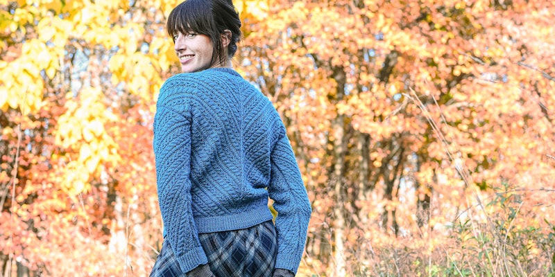 Woman in aqua cabled cardigan looking over her shoulder