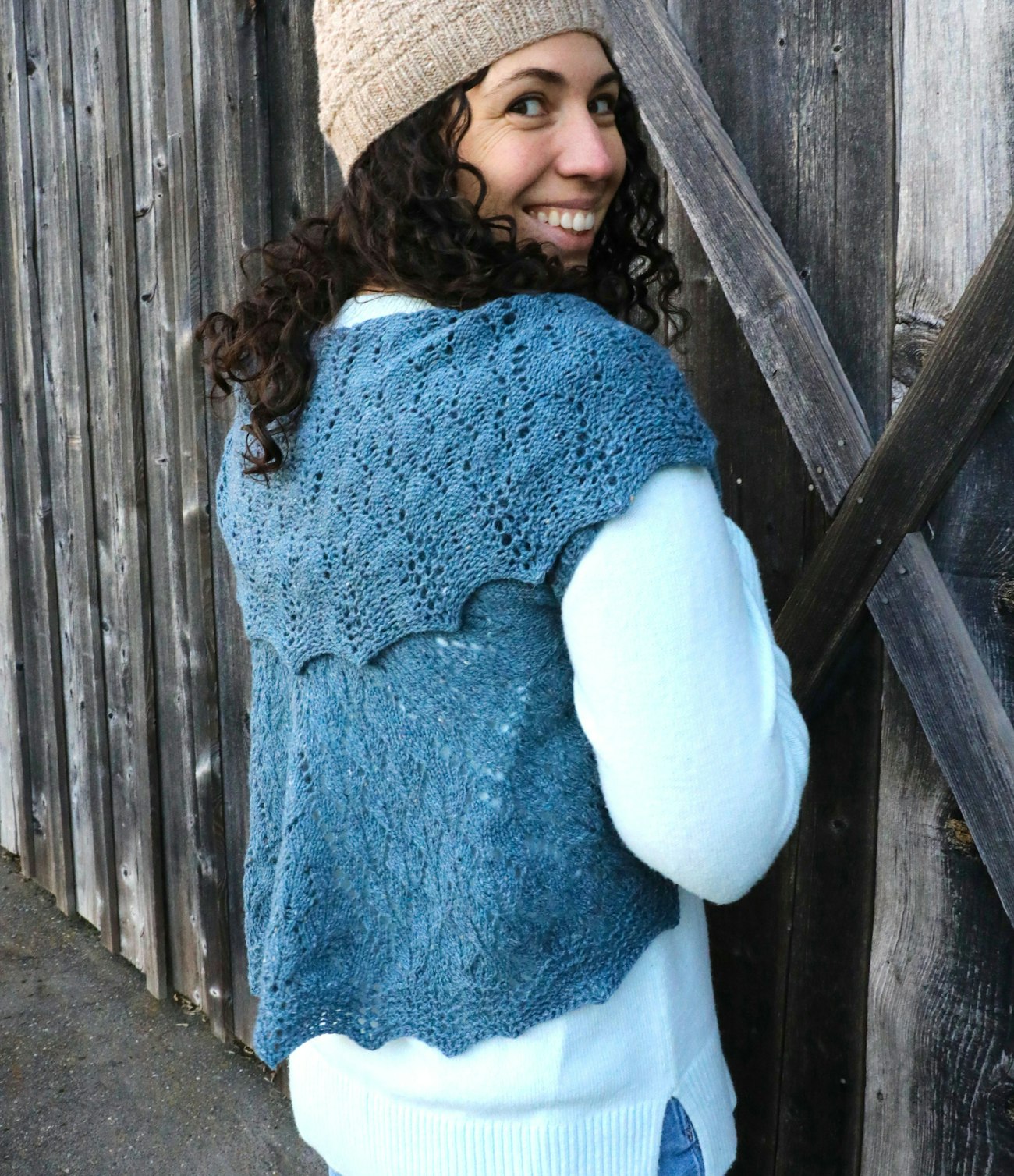 Woman with curly dark hair wearing blue-green knitted wrap