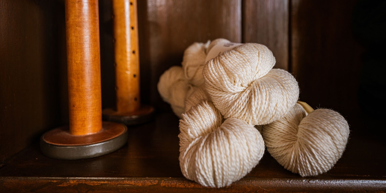 2 wooden spools and 3 skeins white wool