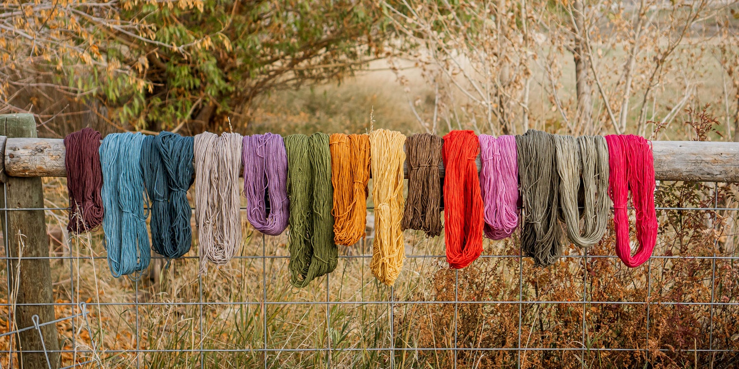 Skeins of colorful wool hanging on a wooden fence