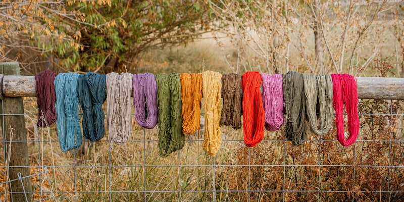 Skeins of colorful wool hanging on a wooden fence