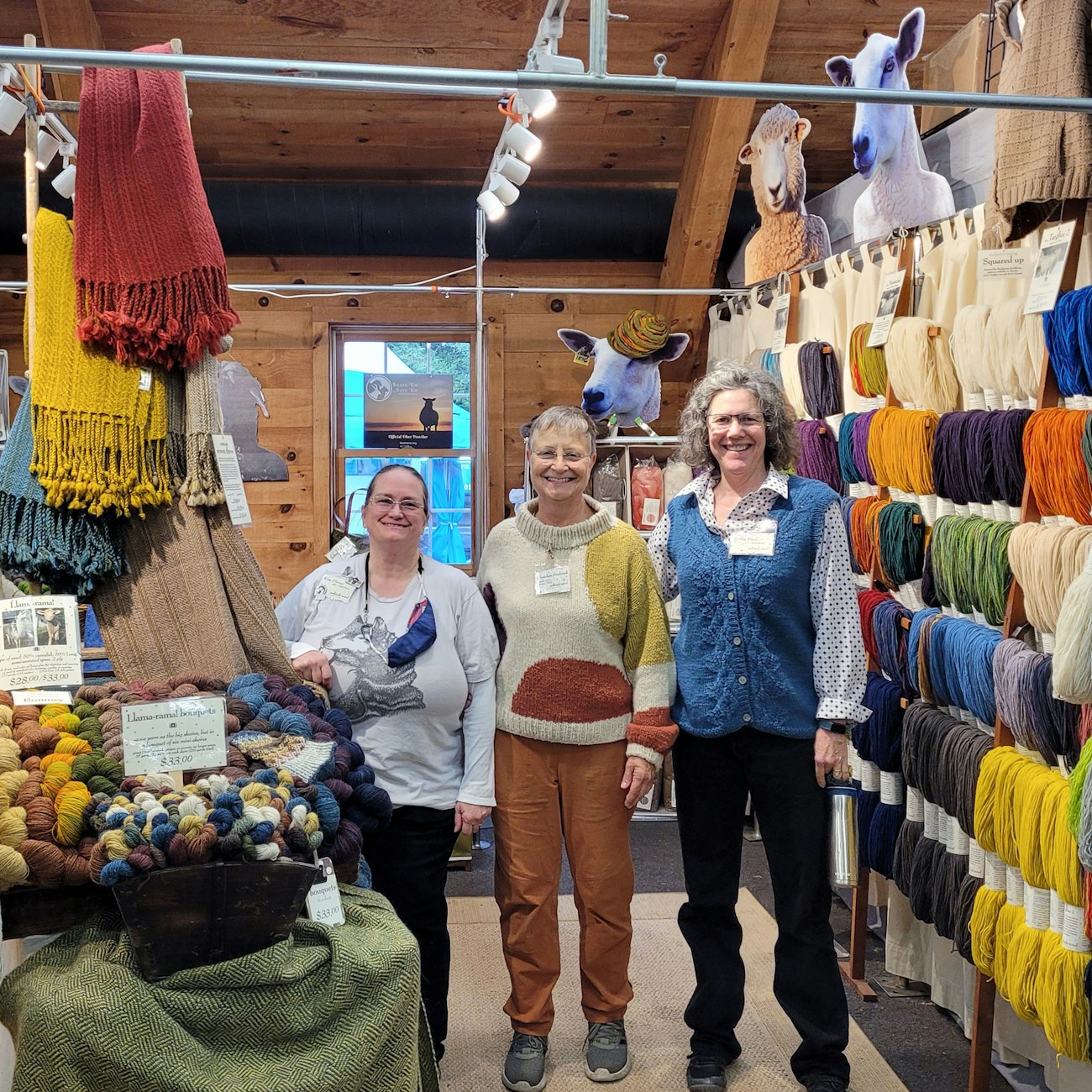 Three women in booth filled with yarn and wool products