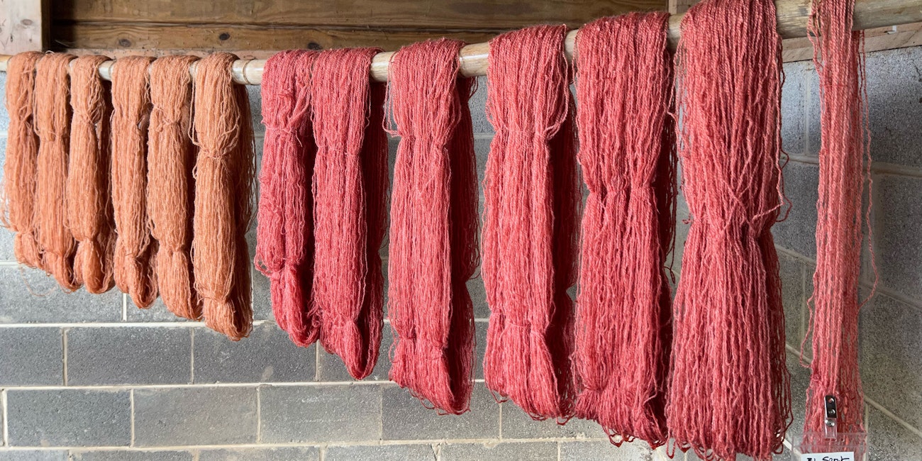 Orange and red yarn hanging on a pole