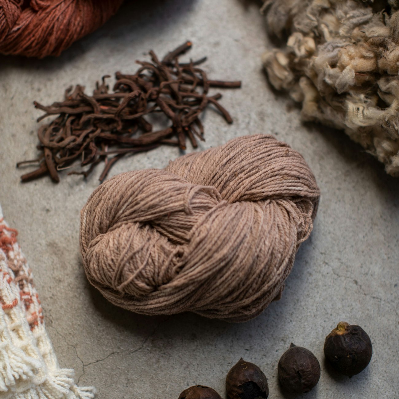 Brown yarn, unwashed wool, madder root, and other natural dyes and naturally dyed yarn