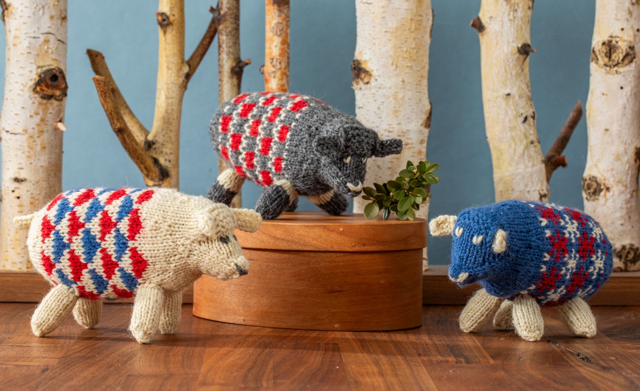 white, gray, and blue colorwork knitted sheep in wood background scene