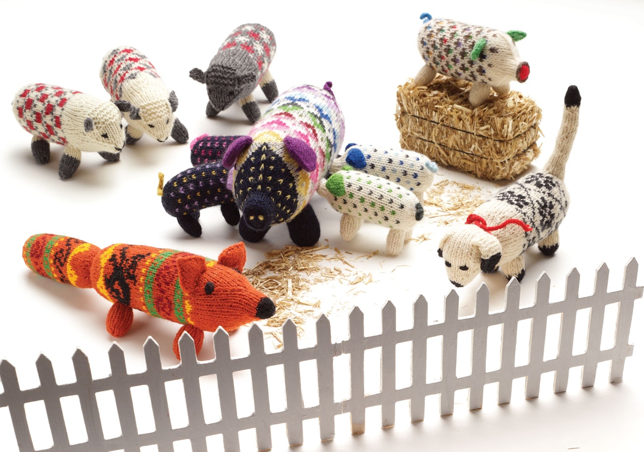 Brightly colored knitted farm animal toys including pigs, sheep, a fox, and a dog.