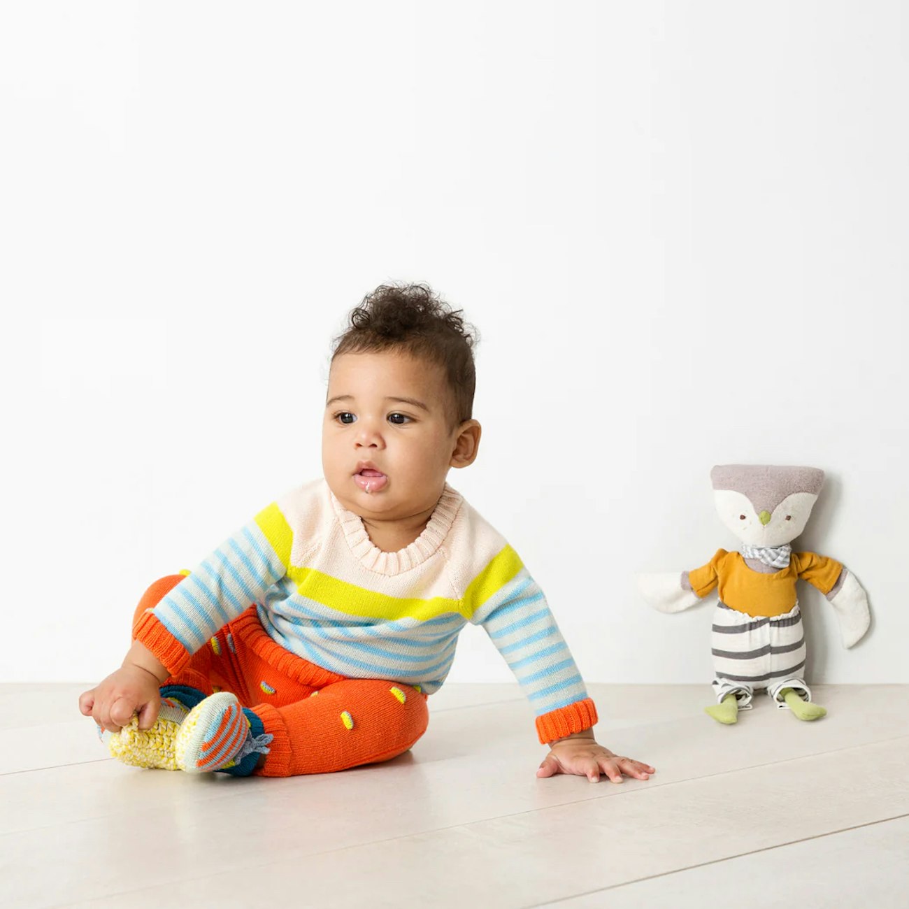 Baby in striped sweater with orange textured knitted leggings