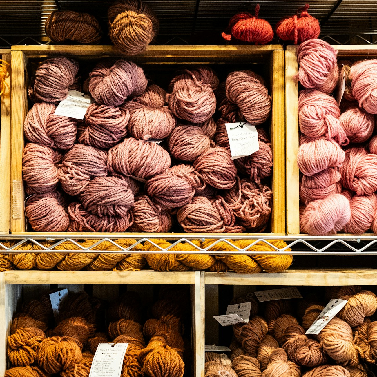 Crates of rose, pink, orange, and tan wool yarn