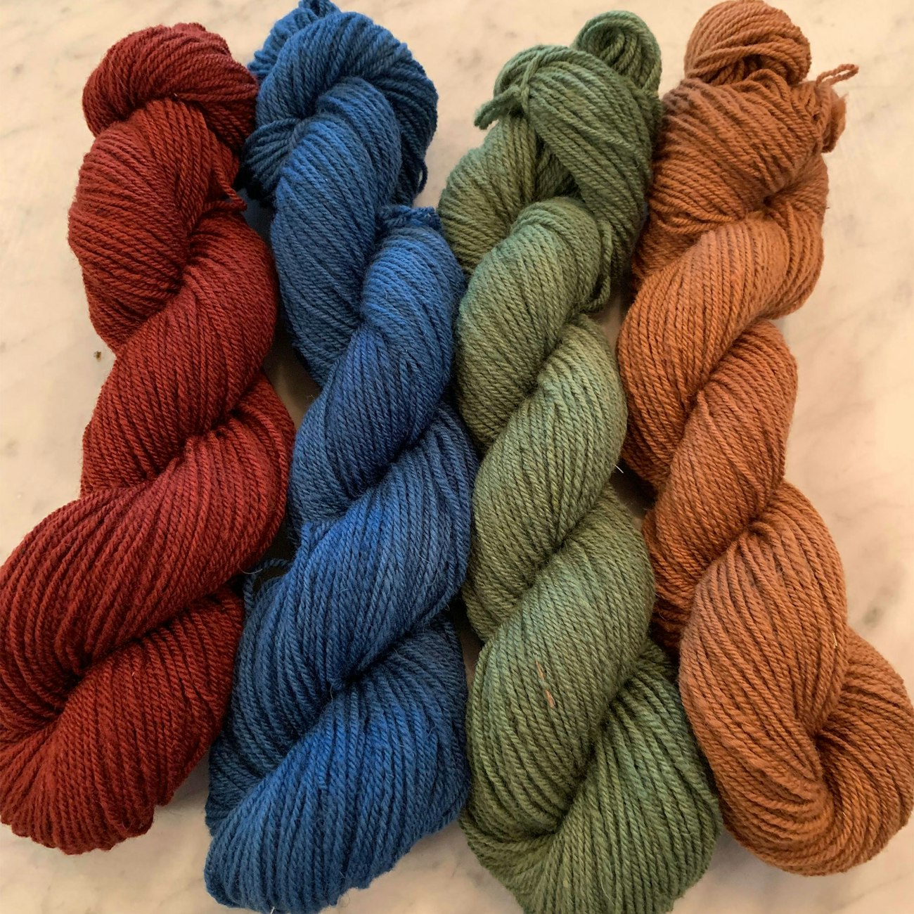 Red, blue, green, and orange skeins of Polypay yarn on a table
