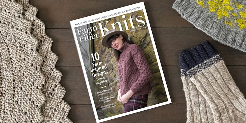 A magazine rests on a table, surrounded by knit items.