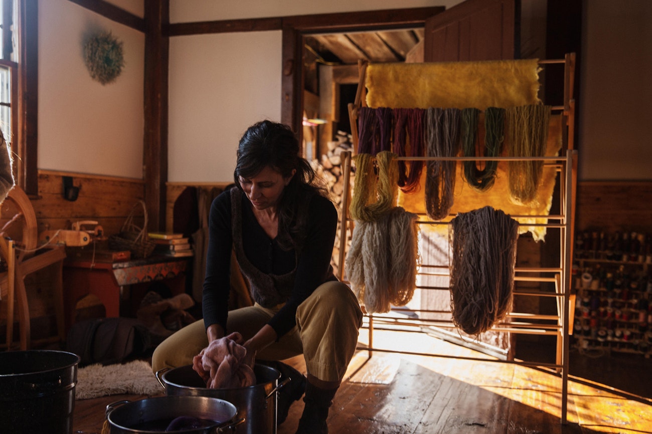 Woman in black shirt with hands in dye pot in historic home