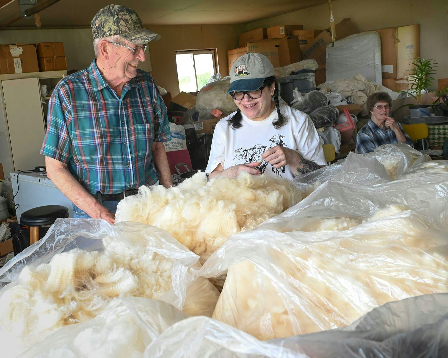 Don Reichert and Andrea Panzica admire the 2024 Corriedale fleeces as Linda looks on.