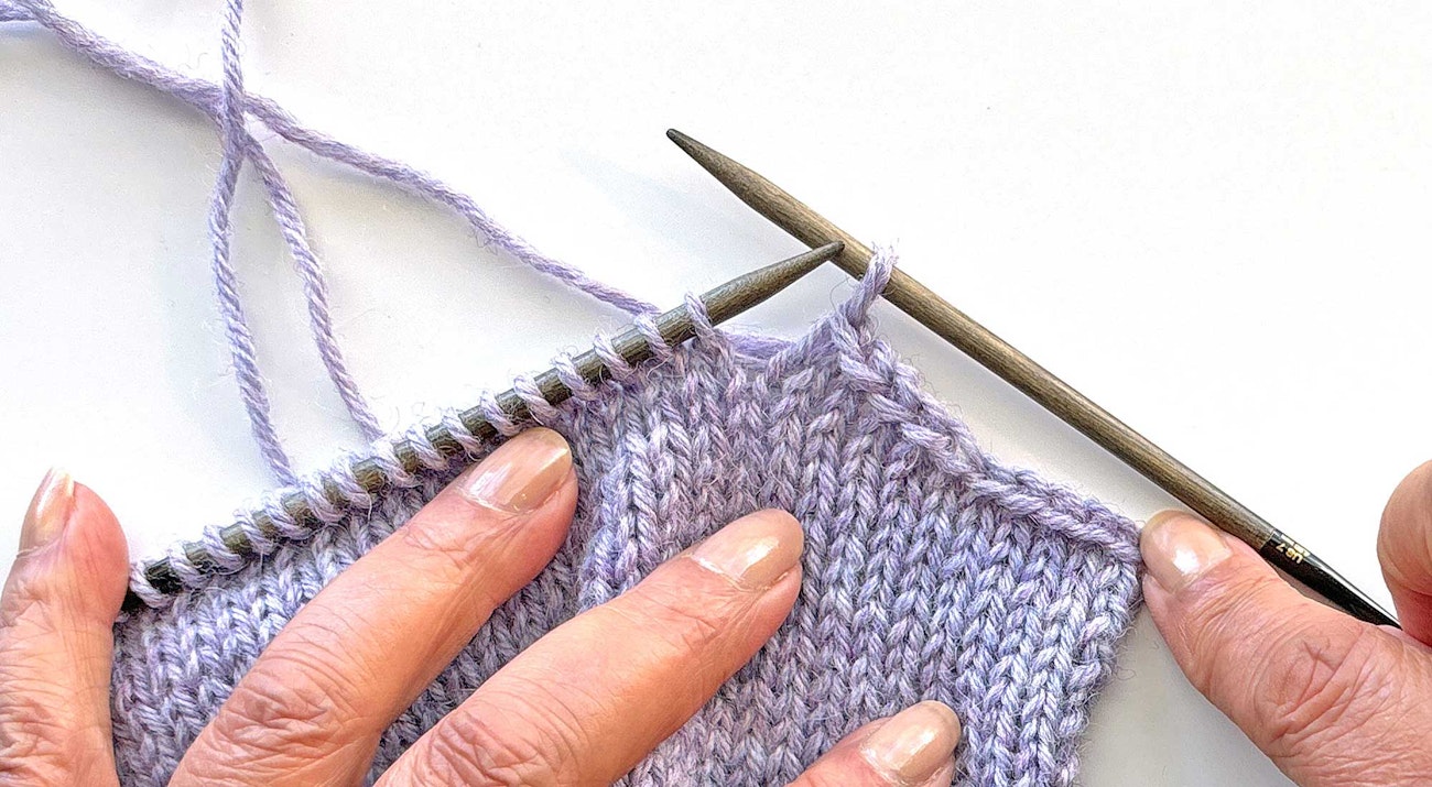 purple knitted swatch on knitting needles