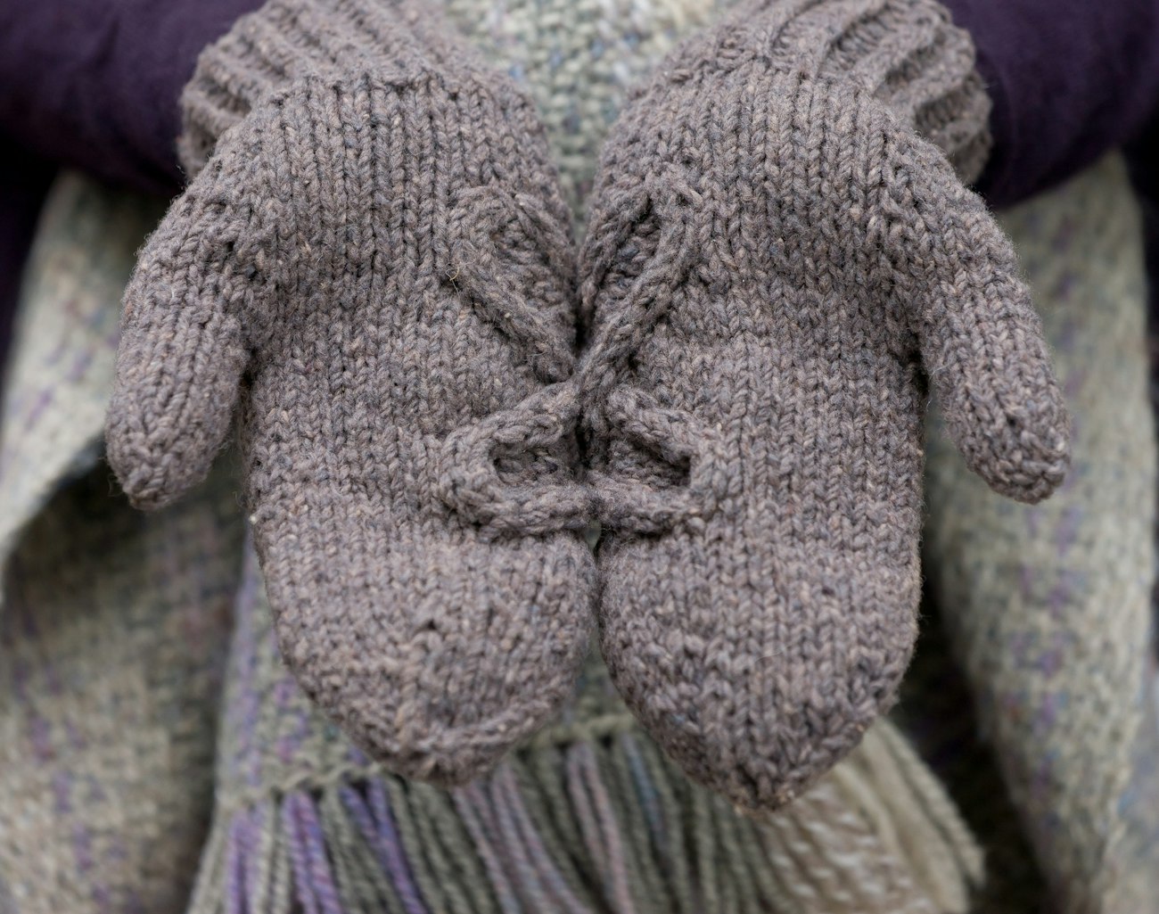 Hands in gray cabled mittens
