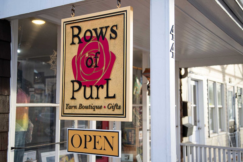 A sign that reads "Rows of PurL" hangs from a shop awning.