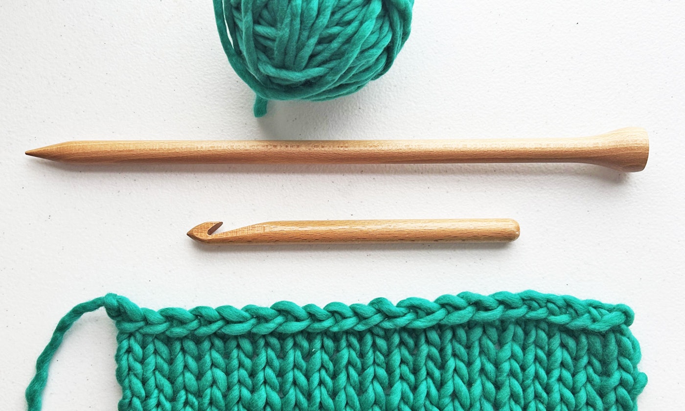ball of green yarn, tools, and knitted swatch
