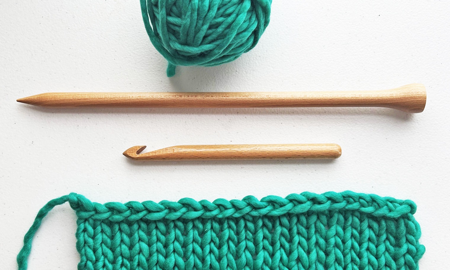 ball of green yarn, tools, and knitted swatch