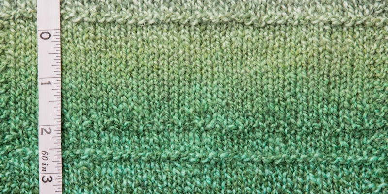 Green marled yarn swatch with tape measure on left side