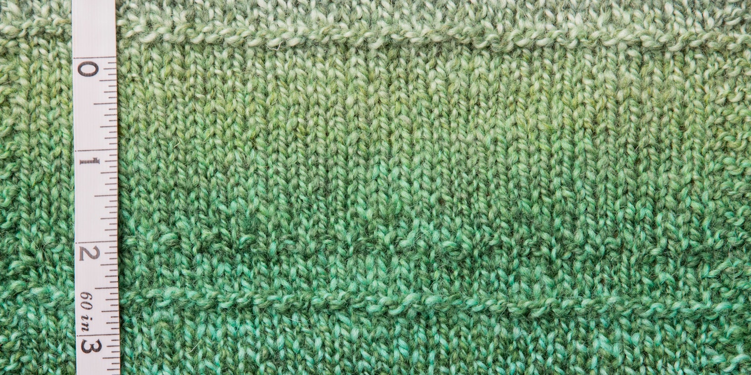 Green marled yarn swatch with tape measure on left side