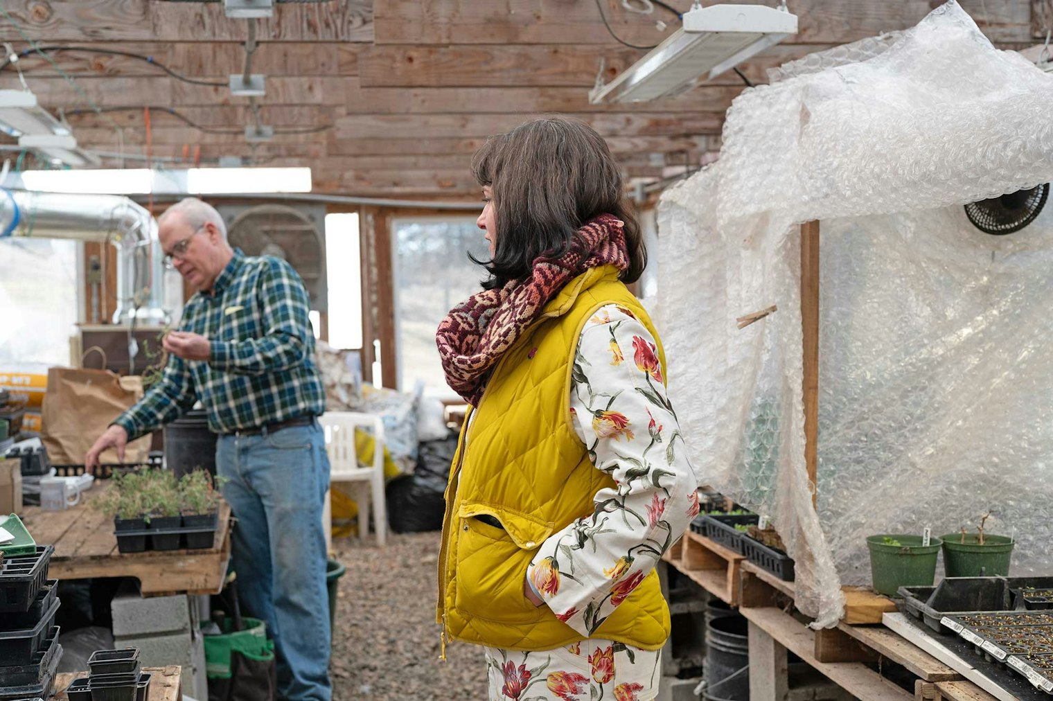 Kelly is ready to model the Clover Ridge Cowl while Mark checks on some of the seedlings.