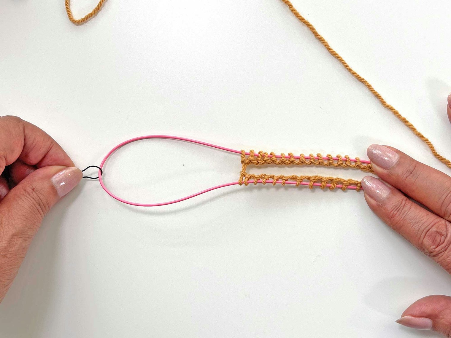 Use one hand to hold the stitches on the cord, and use the other hand to grasp the stitch marker and pull, forming a loop of cord between the stitches.